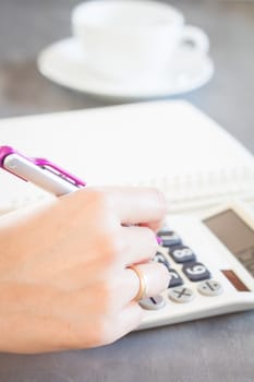 Hand holding pen and pressing calculator buttons, stock photo