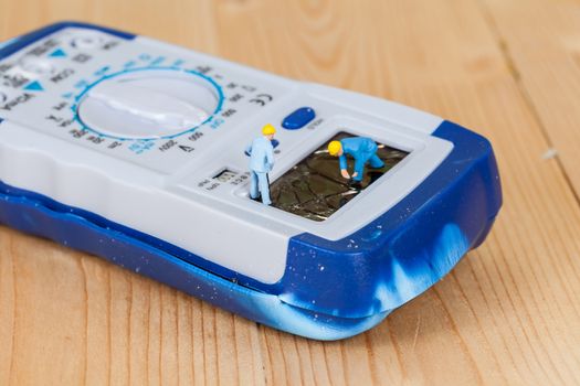 miniature maintenance team repairing a broken Digital multimeter