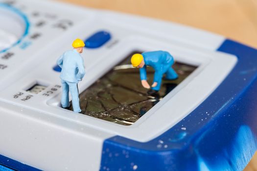 miniature maintenance team repairing a broken Digital multimeter