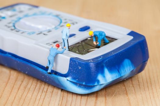 miniature maintenance team repairing a broken Digital multimeter
