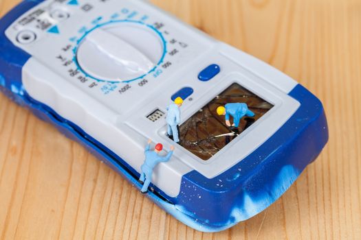 miniature maintenance team repairing a broken Digital multimeter