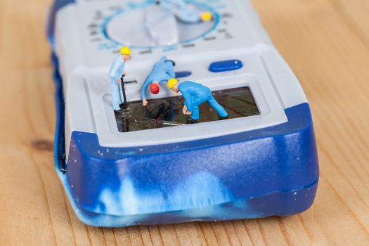 miniature maintenance team repairing a broken Digital multimeter