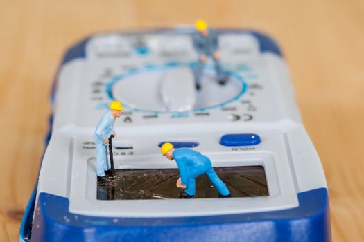 miniature maintenance team repairing a broken Digital multimeter
