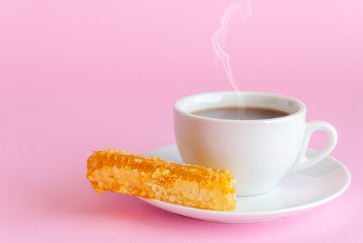 Cup of hot tea and honeycomb on pink background