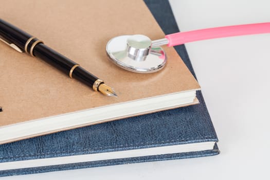 Diary with  pen and stethoscope isolated on white background