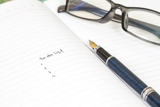 writing to do list on notebook page with pen on wood background