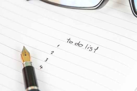 writing to do list on notebook page with pen on wood background