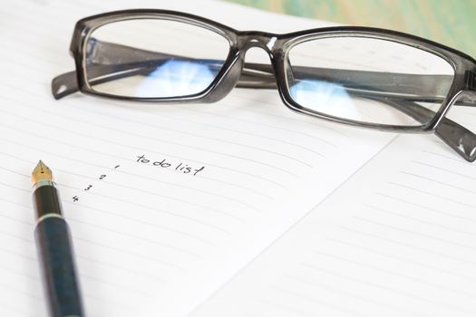 writing to do list on notebook page with pen on wood background