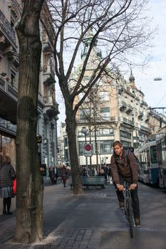 Zurich, Switzerland - November 27, 2011. A young man riding a bicycle on business.