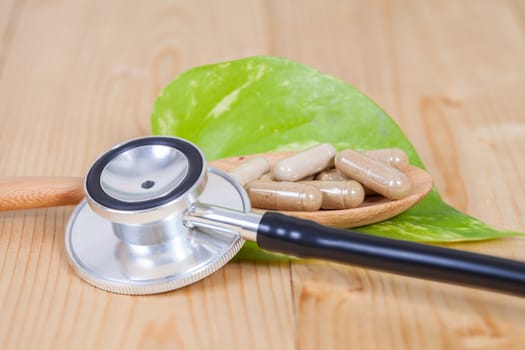 Capsules of herbs on spoon and stethoscope
