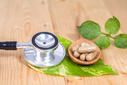 Capsules of herbs on spoon and stethoscope