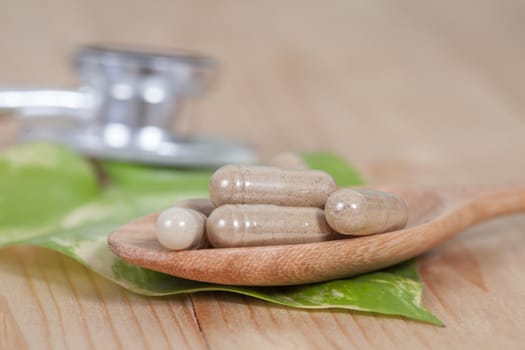 Capsules of herbs on spoon. healthy eating for healthy 
living.
