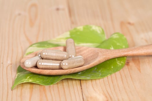 Capsules of herbs on spoon. healthy eating for healthy 
living.