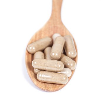 Capsules of herbs on spoon. healthy eating for healthy 
living.