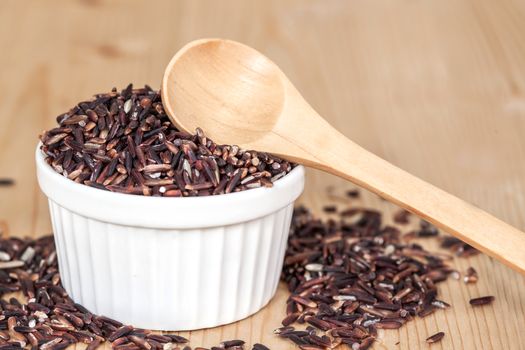 Rice berry in bowl on wood background