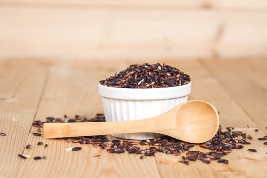 Rice berry in bowl on wood background
