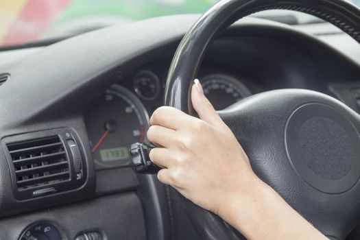 Arm girls with trendy manicure holds the steering wheel in the car.