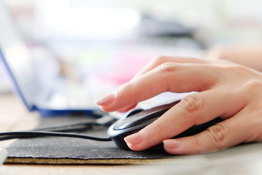 Macro shot of a woman hand using a computer mouse.