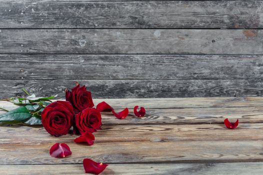 Beautiful three red rose flowers with petal on rustic table