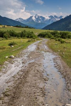 Road in valley after rain, mountains in the background