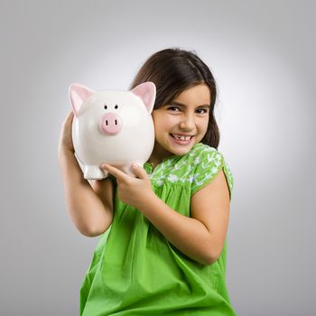 Beautiful and happy young girl holding a piggybank