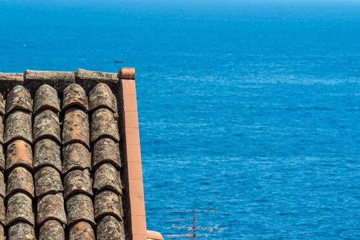 detail of an ancient Italian roof over the blue sea