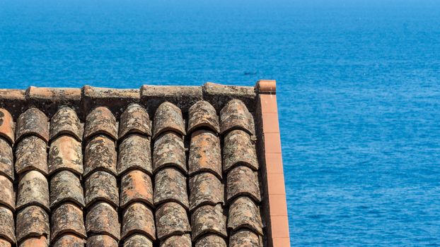 detail of an ancient Italian roof over the blue sea