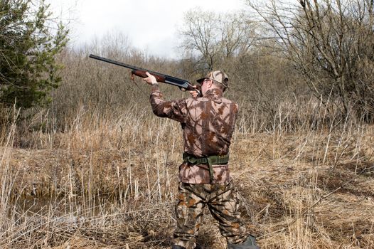 Outdoor shot of man aiming a shotgun.