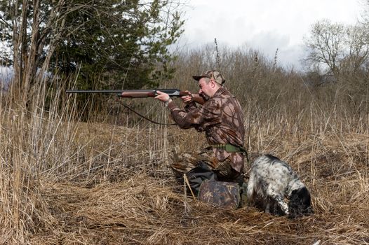 Outdoor shot of man with a gun and Russian hunting Spaniel.