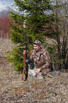 Outdoor shot of man with gun and Russian hunting Spaniel.