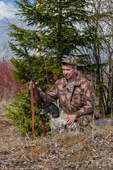 Outdoor shot of man with a gun and Russian hunting Spaniel.