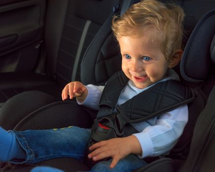 Baby boy 8 months old smiling in a safety car seat.