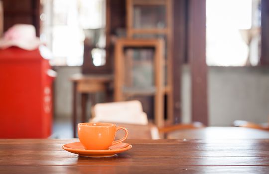 Orange coffee cup on wooden table in coffee shop