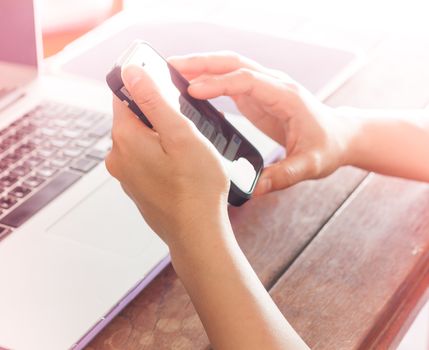 Woman using smart phone and laptop on work station
