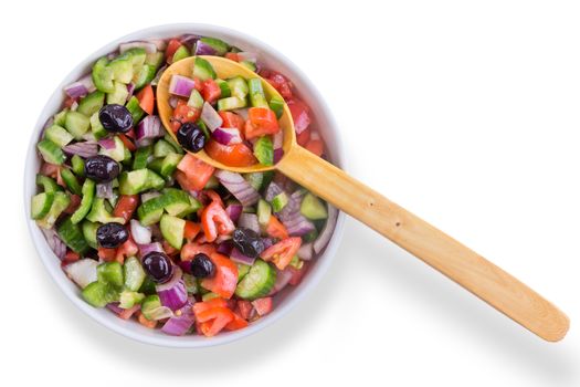 Fresh colorful Turkish shepherd salad with olives served in a round bowl with a wooden serving spoon as a healthy accompaniment to a meal, overhead on white