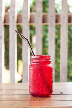 Iced drink in red glass on wooden table with vintage filter, stock photo