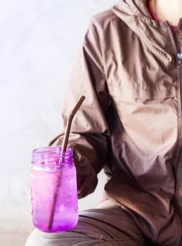 Woman hand holding iced drink in violet glass with vintage filter,  stock photo