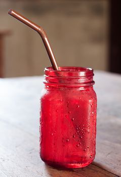 Iced drink in red glass on wooden table, stock photo