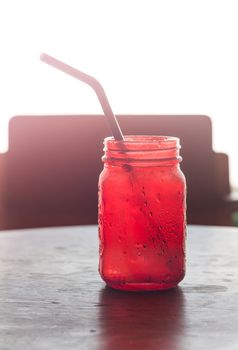 Iced drink in red glass on wooden table with vintage filter, stock photo