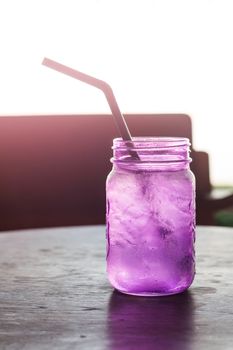 Iced drink in violet glass in coffee shop with vintage filter, stock photo