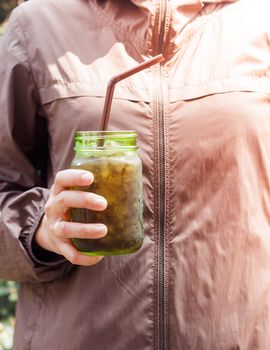 Woman hand holding iced soda in green glass with vintage filter, stock photo