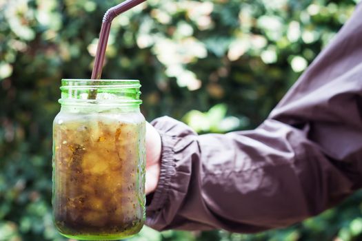 Woman hand holding iced soda in green glass, stock photo