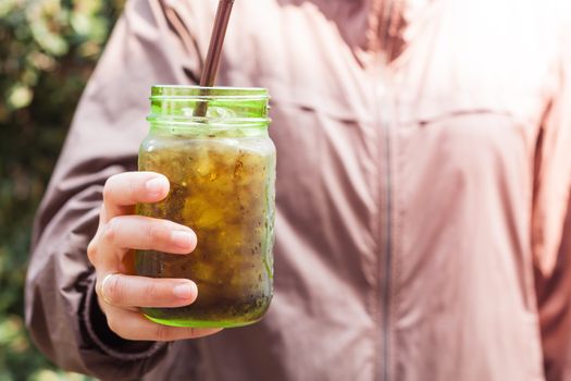 Woman hand holding iced soda in green glass with vintage filter, stock photo