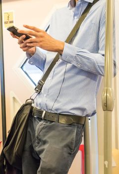 Businessmen using their cell phones on thailand subway. Horizontal composition. Business travel and communication concept.