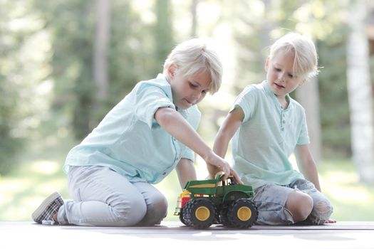 Little brothers playing with toy cars outdoors