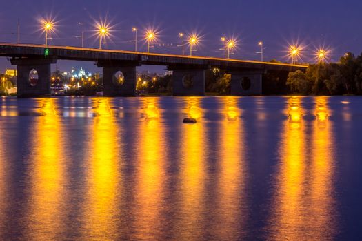 Night bridge lights reflected in river water. HDR