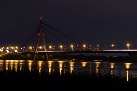 Night bridge with lights reflecting in river waters