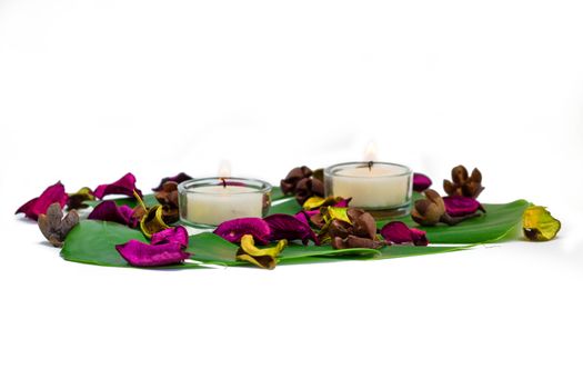 Fresh colorful composition of two burning candles, fragrant potpourri on monstera leaf