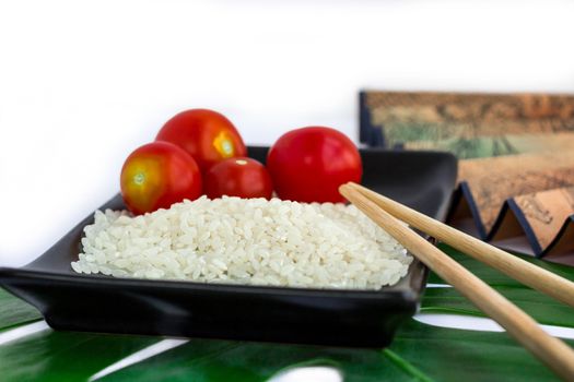 Oriental composition of rice, tomatoes, chopsticks, green leaf and transp isolated on white background