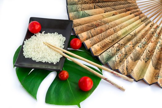 Oriental composition of rice, tomatoes, chopsticks, green leaf and transp isolated on white background